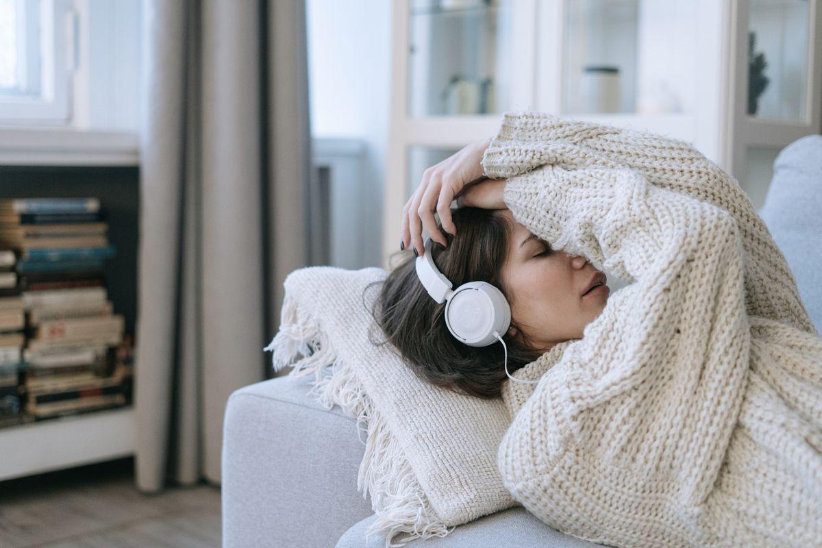 Mujer descansando con auriculares y una manta, en un momento de calma