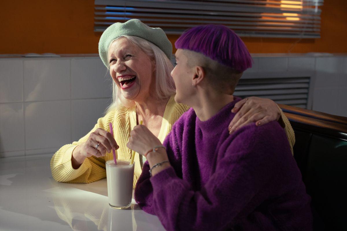 Dos familiares adultas riendo juntas mientras toman algo en una cafetería